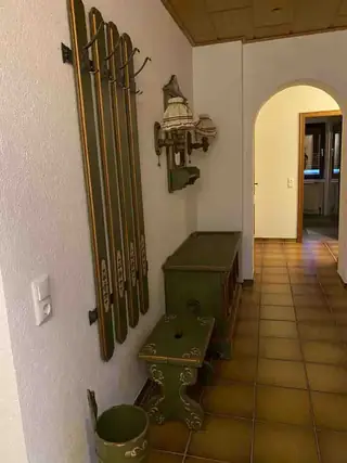 Eingangsflur mit handbemalter grüner Holzgarderobe, Truhe und Hocker im Landhausstil.